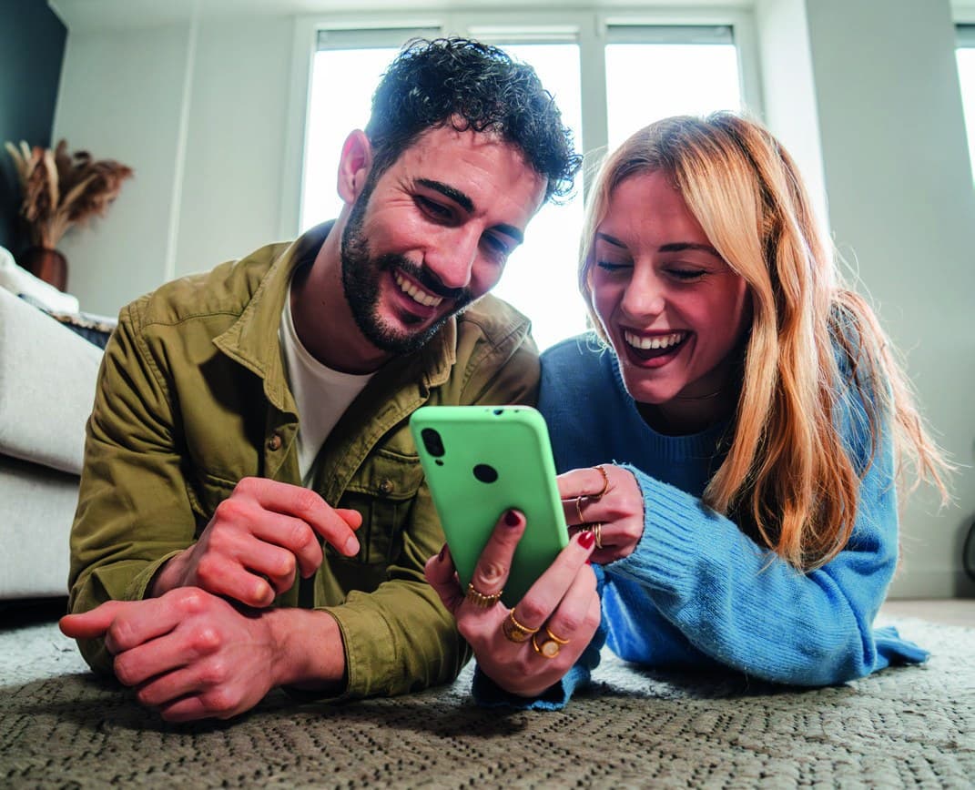 Couple pilotant ses volets roulants depuis un smartphone